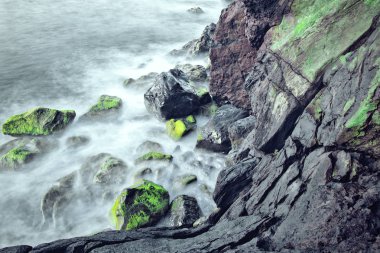 Deniz dalgaları plajda kayaya çarpıyor..