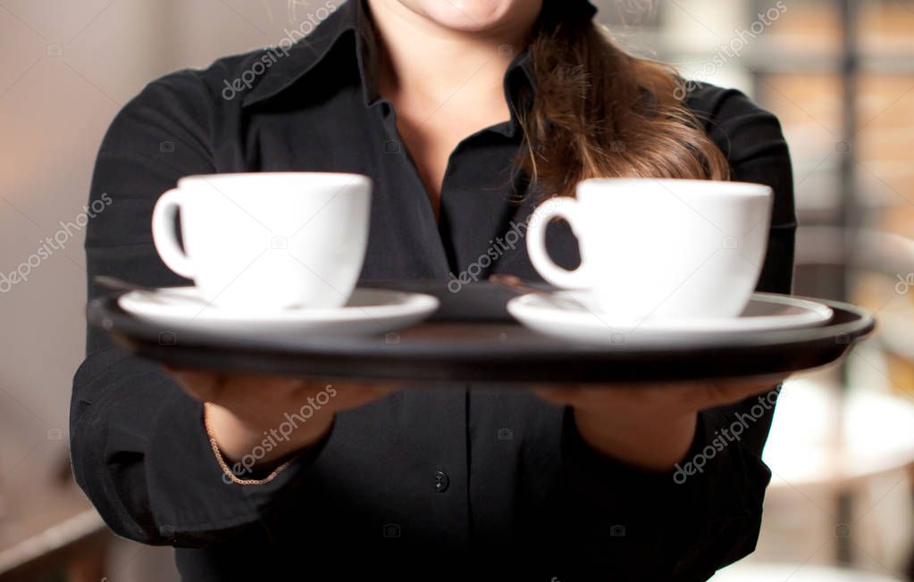Portrait of waitress holding tray of coffee cups in cafe