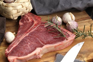 Ham T-bone biftek görmüş baharat ve taze otlar ile ahşap bir gemide görev yaptı.