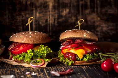 Siyah burger patty et, peynir, domates, mayonez. Koyu ahşap rustik masa. Modern hızlı yiyecek öğle yemeği.