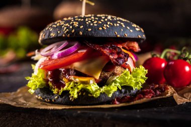 Siyah burger patty et, peynir, domates, mayonez. Koyu ahşap rustik masa. Modern hızlı yiyecek öğle yemeği.