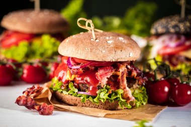 Siyah burger patty et, peynir, domates, mayonez. Koyu ahşap rustik masa. Modern hızlı yiyecek öğle yemeği.