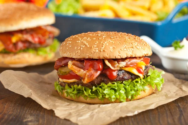 Close-up of home made burgers with french fries on old wooden table closeup.