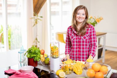 Genç gülümseyen kadın evde mutfak blender Smoothie taze yeşillikleri ile yapma.