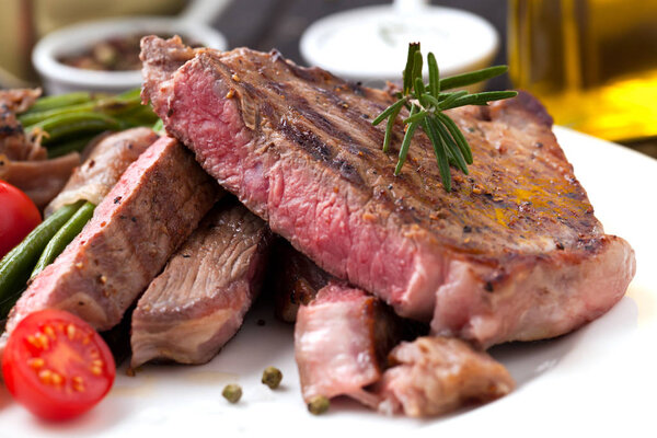 Juicy rib-eye steak with potato wedges and french beans