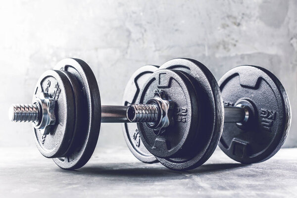 Closeup shot of two dumbells placed on dark Grey surface