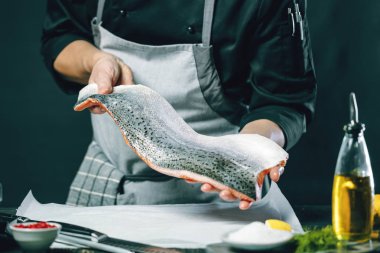 Büyük somon, aşçının elindedir. Somon fileto dilimlemek için bıçak kullanıyor. 