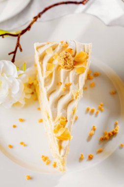 Vanilyalı kek krem ve beyaz çikolata ile süsleyin. Çocuk oyuncağı beyaz tabağa dilimlenmiş. Ahşap masaya servis. En sevdiğin tatlı için kutlamak olay veya Doğum günü partisi.