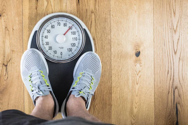 Men standing on weigh scales at gym.Waist measurement by tape measure .Concept of healthy lifestyle.