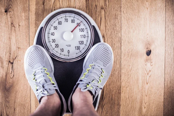 上に立っている男性のジムで体重計の重量を量る 巻尺によるウエスト測定 健康的なライフ スタイルのコンセプト — ストック写真