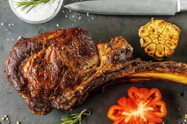 Taze biberiye ve domates görünümü kadar yakın bir kalbur üzerinde nadir ızgara veya mangalda tomahawk sığır eti biftek dilimlenmiş