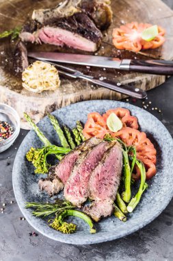 Barbekü kuru wagyu tomahawk bifteği ve ahşap bir tahtanın üstünde yeşil kuşkonmaz.