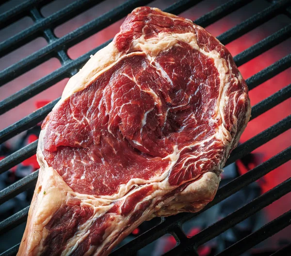 Single tomahawk rib steak on hot black grill