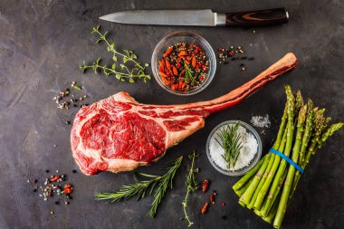 Barbekü kuru wagyu tomahawk bifteği ve ahşap bir tahtanın üstünde yeşil kuşkonmaz.
