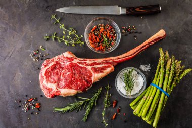 Barbecue dry aged wagyu tomahawk steak with green asparagus as top view on a wooden board clipart