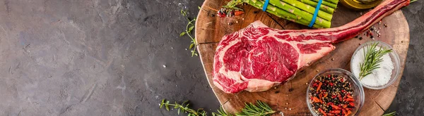 Barbecue dry aged wagyu tomahawk steak with green asparagus as top view on a wooden board