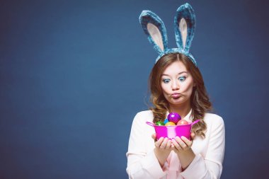 Tavşan kulakları giyen ve renkli bir Easter egg tutan mutlu bir genç kadın stüdyo çekim