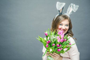 Ev Paskalya celbration concept dekoratif yumurta holding sopa ve lale buquet bir tavşan kulakları adlı genç kadın