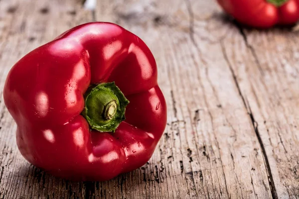 Two red bell peppers on old wooden planks. Rustic take.
