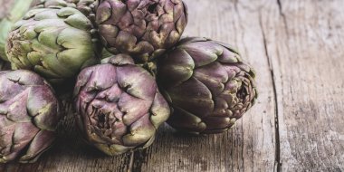 Karanlık rustik ahşap arka plan üzerinde taze mor enginar 