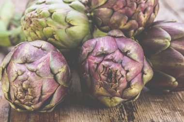 Karanlık rustik ahşap arka plan üzerinde taze mor enginar 