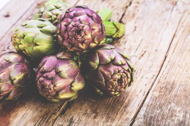 Karanlık rustik ahşap arka plan üzerinde taze mor enginar 