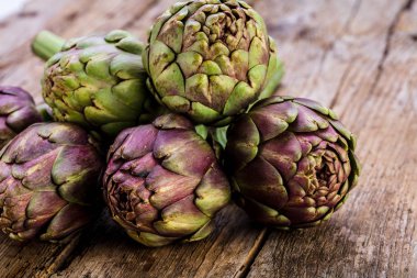 Karanlık rustik ahşap arka plan üzerinde taze mor enginar 