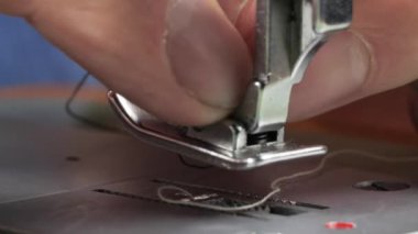 Terzi dikiş makinesine kot pantolon dikiyor, manzarayı kapatıyor.