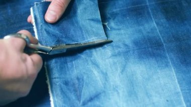 Terzi dikiş makinesine kot pantolon dikiyor, manzarayı kapatıyor.