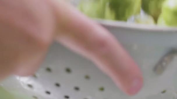 ザルで新鮮な芽キャベツを洗う男性の手のクローズ アップ表示 — ストック動画