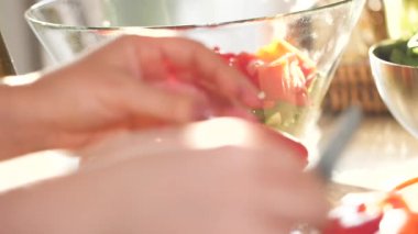 Kadının taze sebze keserken ve mutfakta lezzetli sağlıklı salata pişirirken çekilmiş bir fotoğrafı.