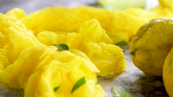 黄色の布 熟したレモンと大理石のテーブルの上の緑の葉 — ストック動画