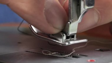 Terzi dikiş makinesine kot pantolon dikiyor, manzarayı kapatıyor.