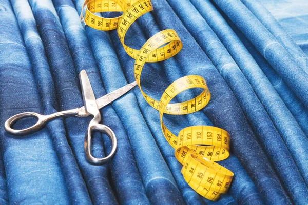 background table top view of sewing tool and jeans on denim fabric.