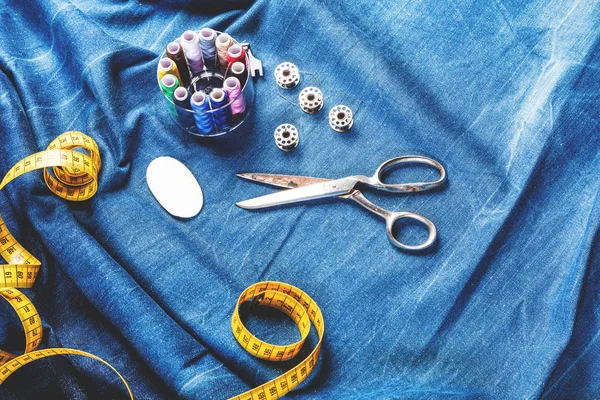 background table top view of sewing tool and jeans on denim fabric.