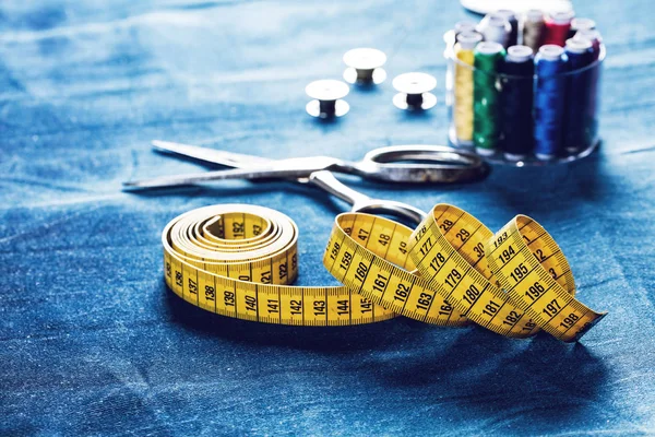 background table top view of sewing tool and jeans on denim fabric.