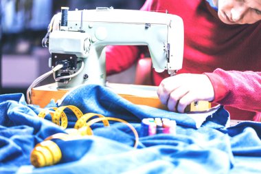 Dikiş makinesiyle kot pantolon dikmek. Kotları dikiş makinesiyle onar. Değişim kotu, kot pantolon paça, el yapımı endüstriyel konsept.