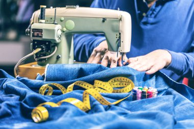 Dikiş makinesiyle kot pantolon dikmek. Kotları dikiş makinesiyle onar. Değişim kotu, kot pantolon paça, el yapımı endüstriyel konsept.