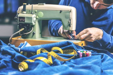Dikiş makinesiyle kot pantolon dikmek. Kotları dikiş makinesiyle onar. Değişim kotu, kot pantolon paça, el yapımı endüstriyel konsept.