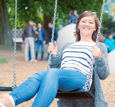 Bahçesi, salıncak üzerinde dinlenme gülümseyen güzel kadın