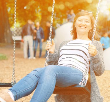 Bahçesi, salıncak üzerinde dinlenme gülümseyen güzel kadın