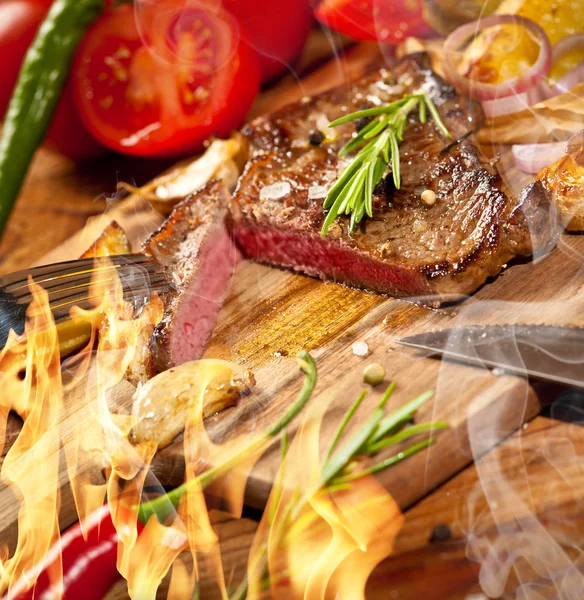 木製のテーブルに火と煙で新鮮なおいしいステーキのクローズ アップ ビュー — ストック写真