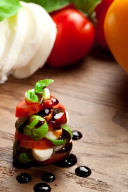 Ahşap masa dilimlenmiş kiraz domates ile mozzarella ve fesleğen yaprakları