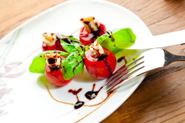 Lezzetli kiraz domates ile mozzarella ve fesleğen yaprakları beyaz tabak içinde