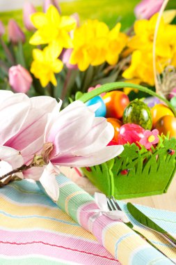 ihale pembe çiçekler, dekoratif parlak renkli boyalı Paskalya yumurtaları sepetle ve çatal bıçak tablo ile  