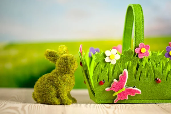green easter bunny and bright decorative basket on wooden surface