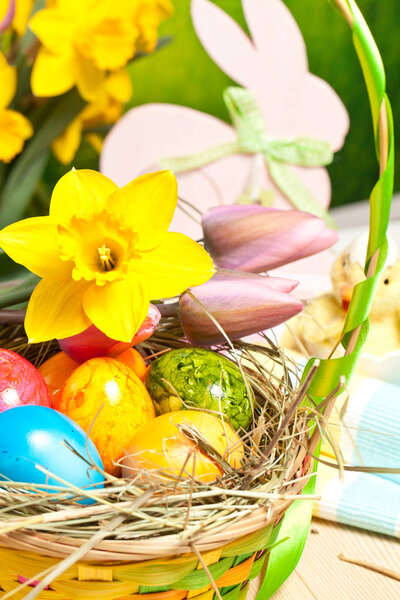 Wooden Easter bunny, colorful eggs and bright flowers. Easter concept