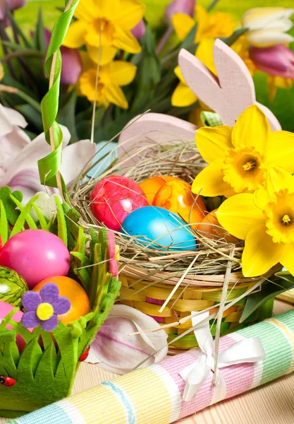 Wooden Easter bunny, colorful eggs and bright flowers. Easter concept