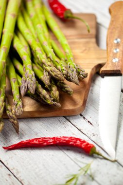 kesme tahtası, bıçak ve biber ahşap masa üzerinde taze sağlıklı kuşkonmaz