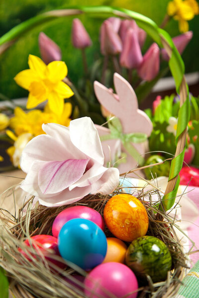 Деревянный пасхальный кролик, красочные яйца и яркие цветы. Пасхальная концепция
